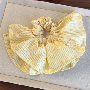 Détail du motif à carreaux jaunes et de la texture plissée du grand chouchou en tissu