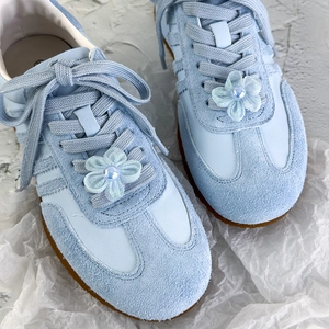 Détail de fleurs en maille bleu clair avec perles sur baskets en daim à rayures