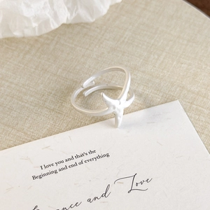Close-up of a silver starfish ring with matte texture on a romantic gift card background