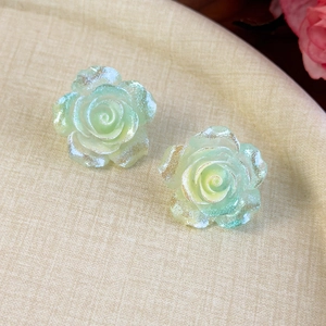 Détail macro de boucles d'oreilles camélia vert menthe avec finition pailletée