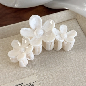 Detailed macro view of the cream white floral hair claw clip on a soft textured tray