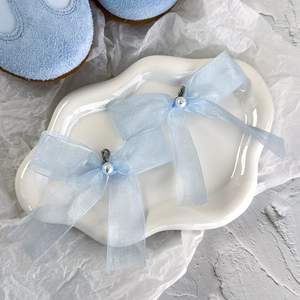 Détail de nœuds de chaussures en organza bleu clair avec perles et clips métalliques