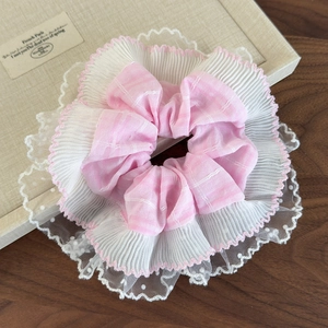 Détail d'un chouchou à carreaux roses avec bordure en dentelle blanche et tulle fin