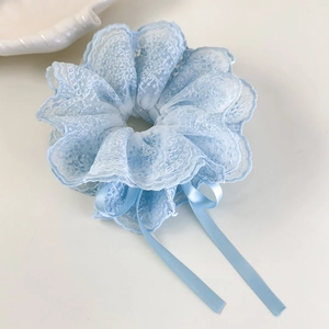 Détail d'un chouchou en dentelle bleu clair avec broderie fine et long ruban élégant