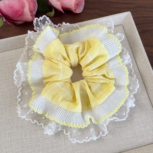 Chouchou à carreaux jaunes avec dentelle blanche sur un plateau avec une rose