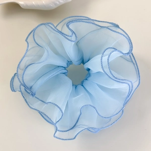 Détail d'un chouchou en dentelle bleu clair avec bords festonnés et texture en organza
