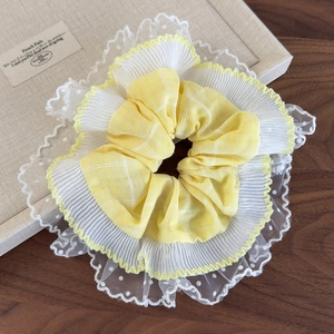 Détail macro du chouchou à carreaux jaune crème avec dentelle blanche et pois fins