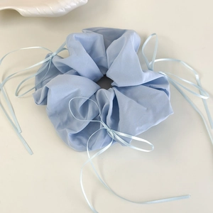 Détail d'un chouchou bleu clair à carreaux en dentelle avec d'élégants rubans suspendus