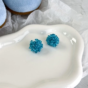Vue macro de boucles de chaussures perlées bleues dans un plat en céramique blanc