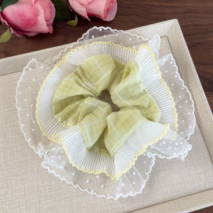 Détail du chouchou en dentelle multicouche avec tissu à carreaux vert clair et bord ondulé