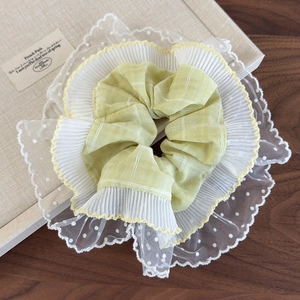 Détail du chouchou à carreaux jaunes avec bordure en dentelle blanche et plis en mousseline
