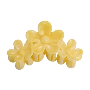 Detail view of yellow floral hair claw clip with cream marble resin texture and shark teeth