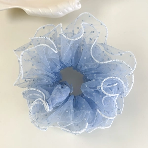 Détail du chouchou en tulle bleu clair à pois blancs avec des bords froissés élégants