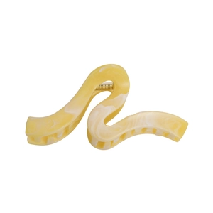 Macro view of large yellow marble texture hair claw clip with golden metal spring