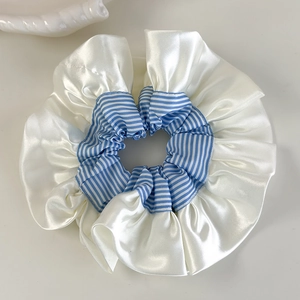 Détail du chouchou en satin blanc et rayures bleues avec reflets nacrés et plis