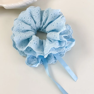 Détail d'un chouchou en dentelle bleu clair avec broderie florale et rubans en satin