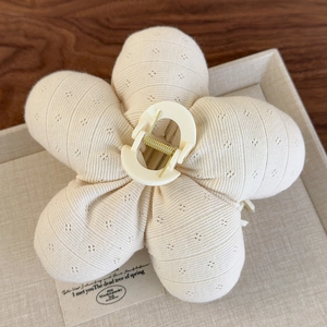 Détail de la pince à cheveux fleur en tissu tricoté crème avec ressort en métal doré