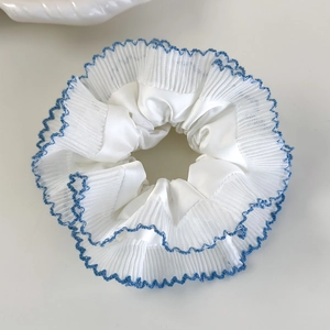 Détail d'un chouchou plissé blanc avec des coutures contrastées bleues délicates