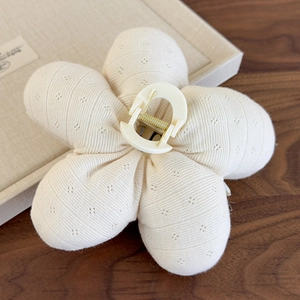 Gros plan détaillé de la pince à cheveux fleur crème avec tissu matelassé et ressort doré