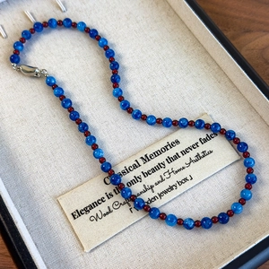 Close-up of blue marble beads and red glass beads necklace with silver ingot clasp