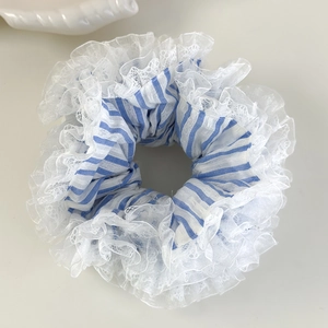 Gros plan du chouchou à rayures bleues avec bords en dentelle blanche sur fond crème