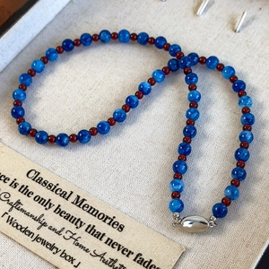Ethnic style necklace with deep blue agate beads, red accents and silver ingot clasp