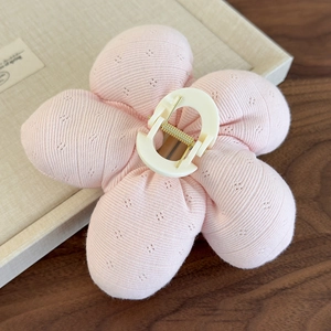 Détail d'une pince à cheveux fleur rose tricotée avec clip en résine et ressort doré