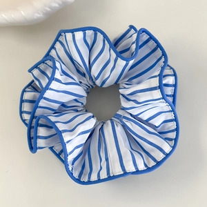 Détail d'un chouchou en dentelle à rayures bleues et blanches avec bordure bleue