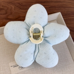 Vue détaillée d'une pince à cheveux en forme de fleur bleu clair en tissu tricoté