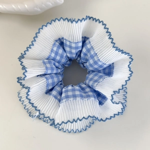 Vue détaillée du chouchou en dentelle à carreaux bleus avec bords ondulés en mousseline