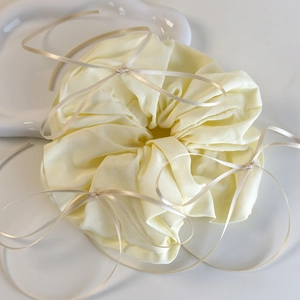 Détail d'un chouchou jaune à fleurs avec nœuds en satin et texture de tissu plissé