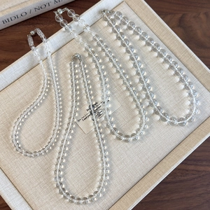 Detail view of four transparent beaded necklaces in varying lengths on a display tray