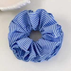 Détail d'un chouchou à rayures bleues et blanches avec bords en dentelle de coton