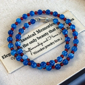 Macro detail of blue marble beads and red glass beads with silver heart-shaped clasp