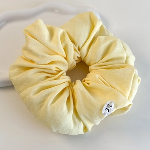 Détail de chouchou jaune à motif floral avec un petit bouton décoratif en nœud
