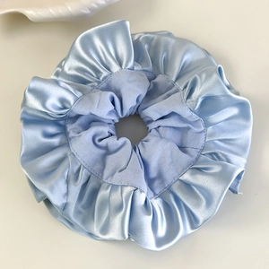 Gros plan détaillé du chouchou en satin bleu clair montrant la texture du tissu