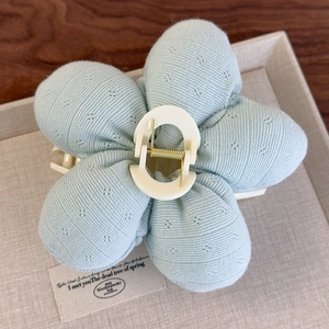 Gros plan sur la pince à cheveux fleurie en tricot bleu menthe à motifs de losanges