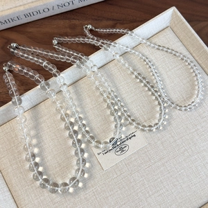 Minimalist transparent acrylic beaded choker necklace set displayed on linen tray