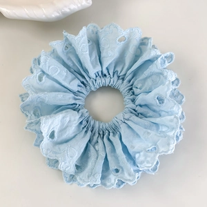 Détail macro du chouchou en dentelle anglaise bleu ciel avec bords festonnés brodés