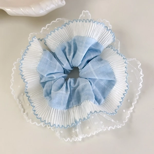 Détail d'un chouchou bleu ciel à carreaux avec volants en tulle multicouches et bords ondulés