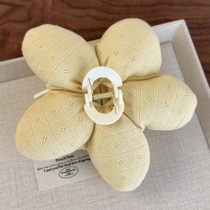Détail de la pince à cheveux fleur jaune avec texture en tissu côtelé et motif à pois