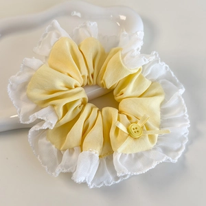 Vue détaillée d'un chouchou jaune avec bord en dentelle et petit nœud décoratif chic