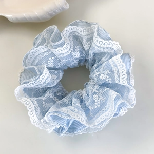 Détail d'un chouchou bleu clair avec broderie de dentelle florale blanche délicate
