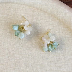 Gros plan de boucles d'oreilles artisanales en perles vert menthe et fil doré