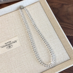 Detail of transparent glass bead choker featuring a silver magnetic clasp closure