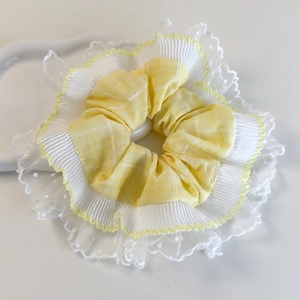 Détail de chouchou jaune à carreaux avec plis blancs et bordure en dentelle délicate