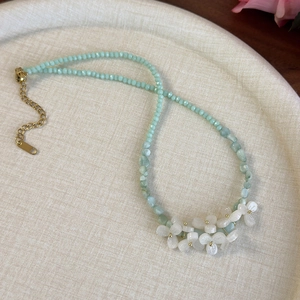 Détail du collier de perles vertes avec des fleurs en nacre sculptées et fermoir doré