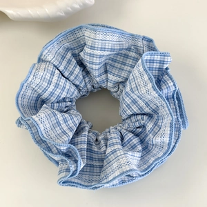 Vue détaillée du chouchou à carreaux bleu et blanc avec bords en dentelle brodée blanche