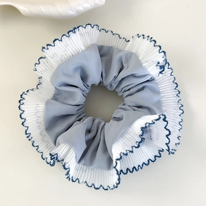 Détail d'un chouchou à carreaux bleus avec bordure en organza blanc et couture ondulée