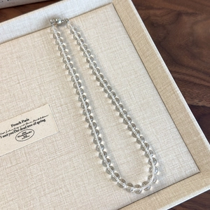 Detailed view of clear acrylic beaded choker with magnetic clasp in a beige jewelry box